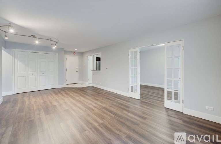 A spacious room with wooden flooring and white walls.