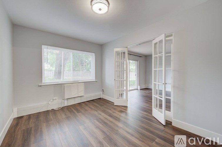 A room with wooden floors and a large window with white blinds.