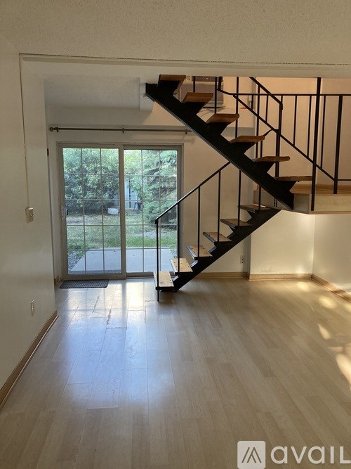 A wooden staircase with metal railings leads up to a door with a glass window.