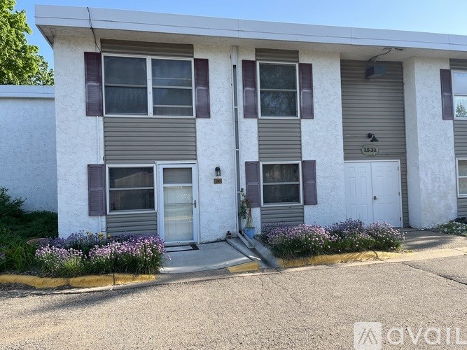A white building with grey and brown trim and a grey roof.