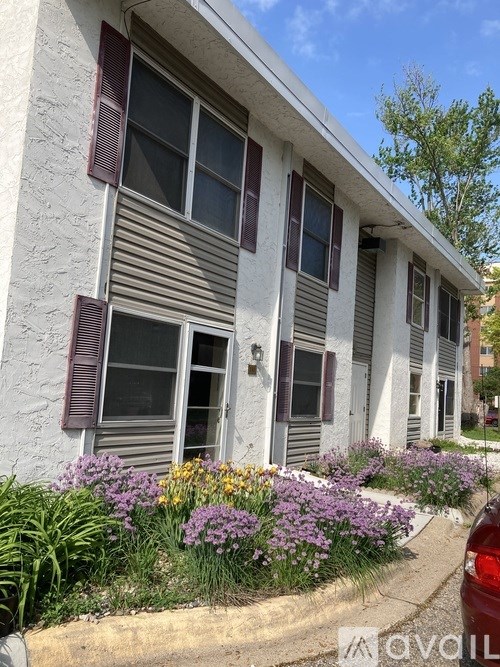 A white house with purple flowers in front.