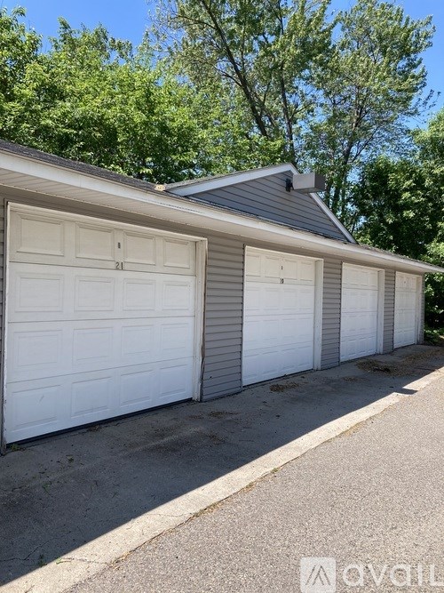 A two-car garage with white doors is situated in front of a house.