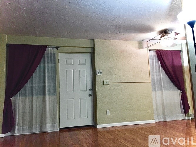 A room with a white door and a ceiling fan.
