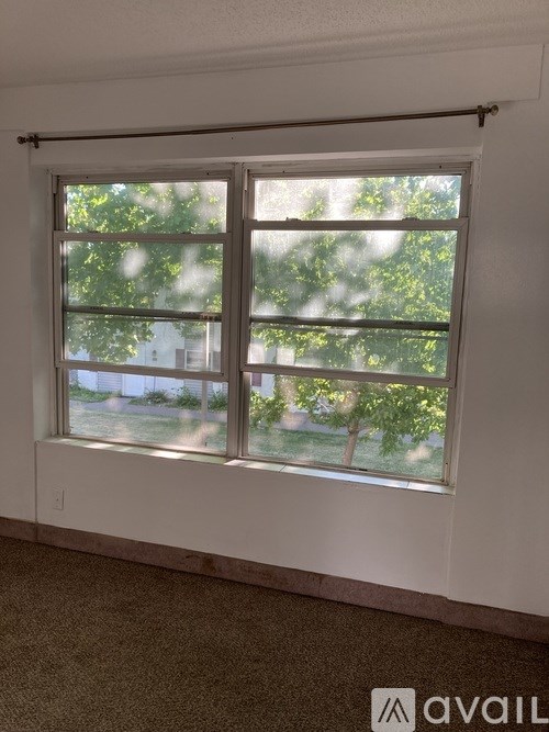 A window with a view of trees and a building outside.