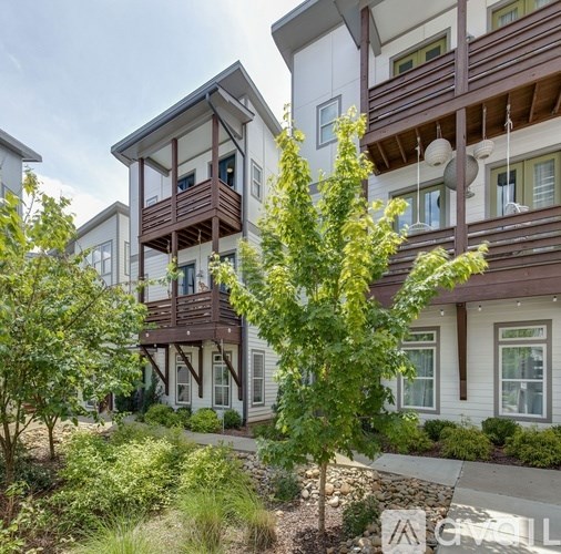 A modern building with a balcony and a tree in front.