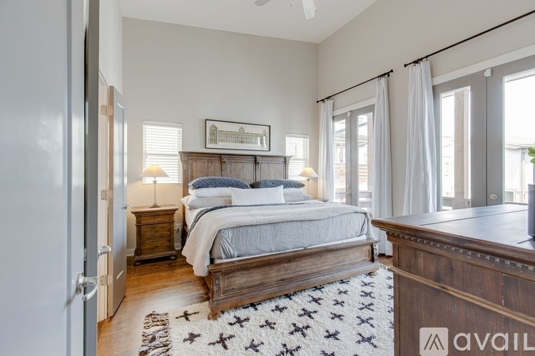 A bedroom with a large bed, a wooden dresser, and a rug with a star pattern.