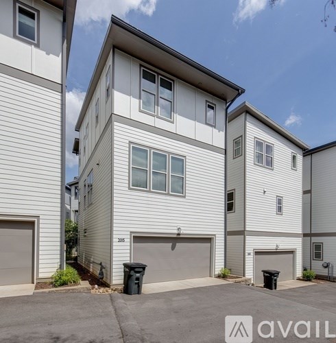 A modern two-story residential building with a garage door and a driveway.