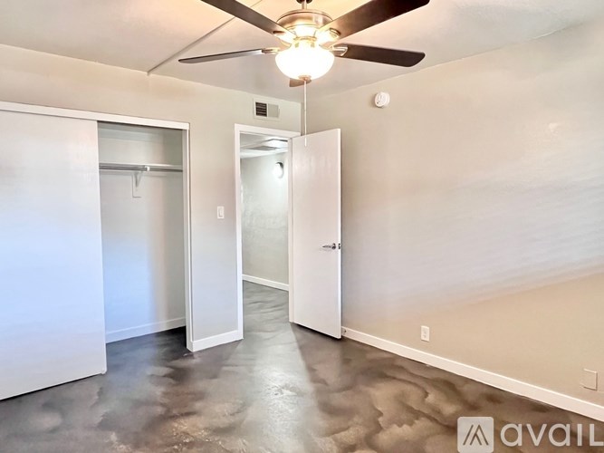A room with a ceiling fan and a door leading to another room.