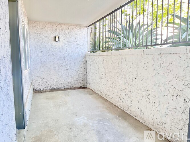 A white room with a grey door and a wall with a hole in it.