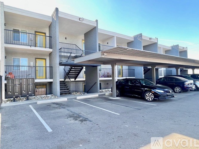 A black car is parked in a parking lot in front of a building.
