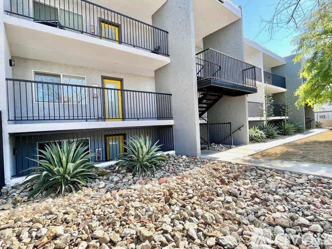 A building with balconies and a rocky area in front.