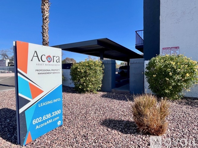A sign for Acora Professional Property Management Services stands in front of a building.