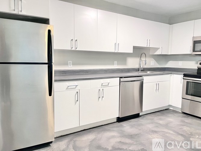 A kitchen with white cabinets and a stainless steel refrigerator.