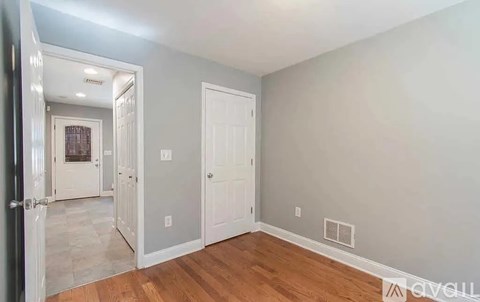 A room with a wooden floor and two white doors.