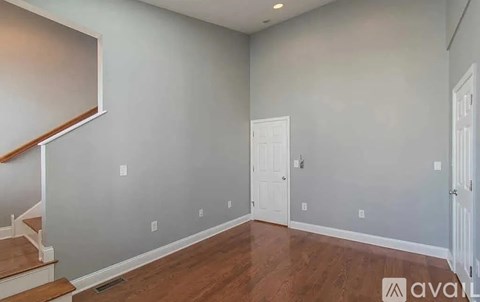 A room with wooden floors and a staircase on the left side.