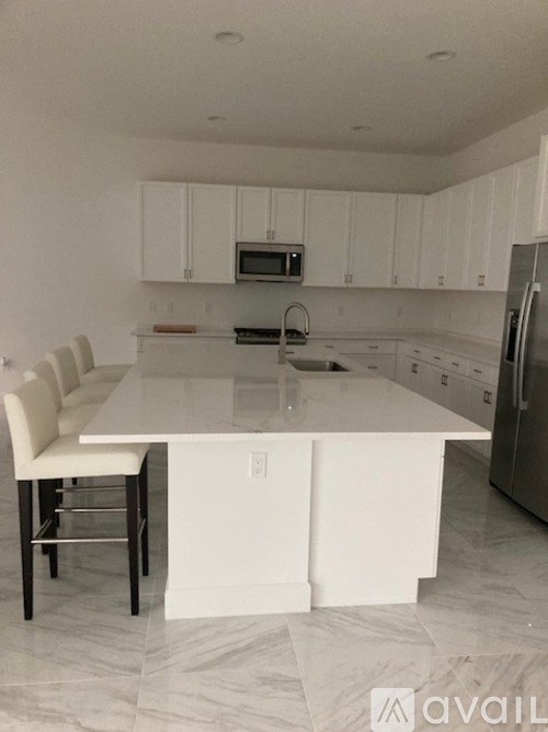 A kitchen with white cabinets and a white island with a chair.