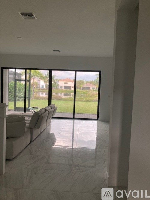 A living room with a couch and a view of the backyard through the windows.