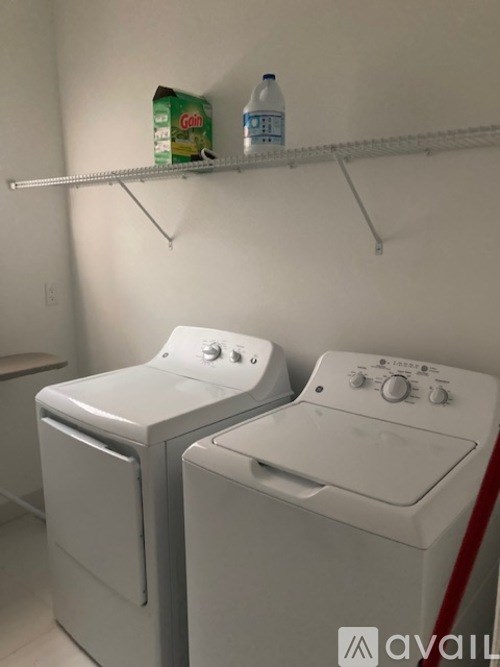 Two white washing machines in a small laundry room.