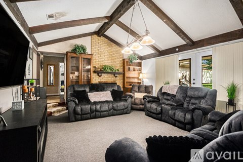 A living room with a black leather couch and a wooden bookcase.