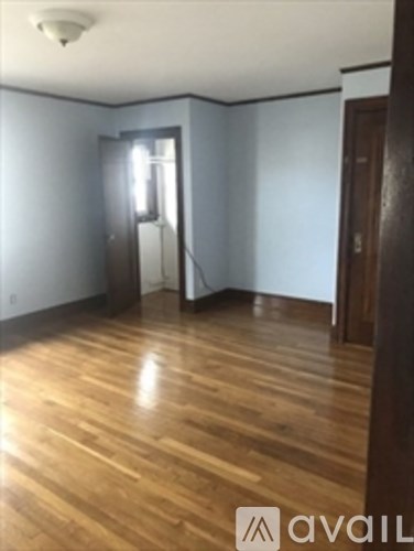 A room with wooden floors and a door leading to another room.