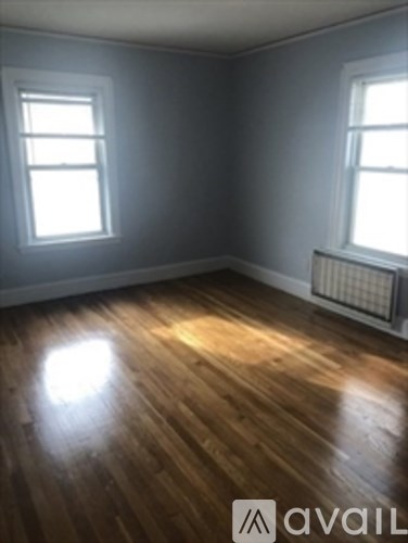 A room with wooden floors and two windows.