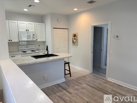 A kitchen with white cabinets and a wooden floor.