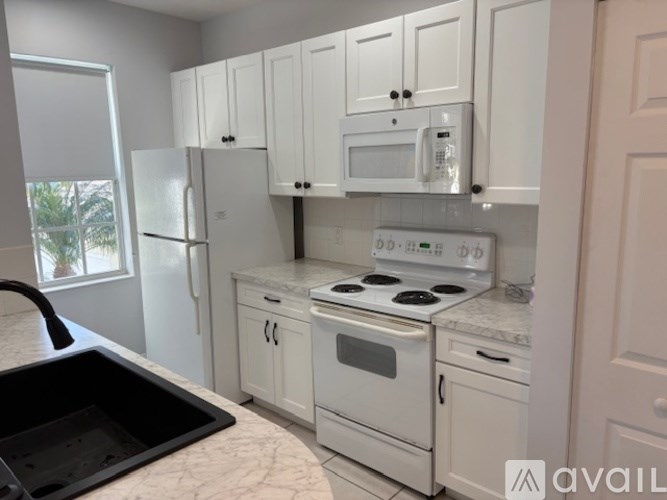 A kitchen with white appliances and cabinets.