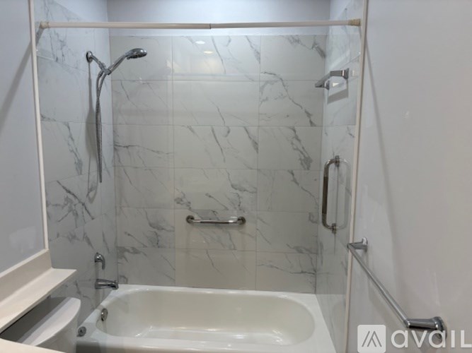 A white marble bathroom with a tub and toilet.