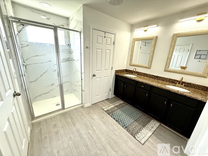 A bathroom with a walk-in shower, double sinks, and a large mirror.