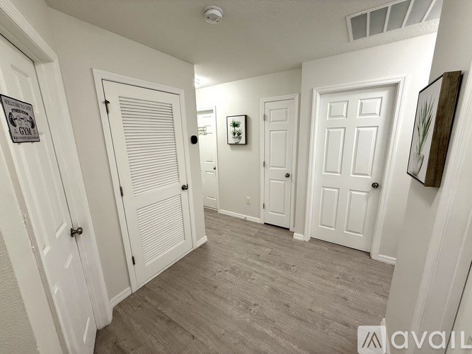 A hallway with white doors and a wooden floor.