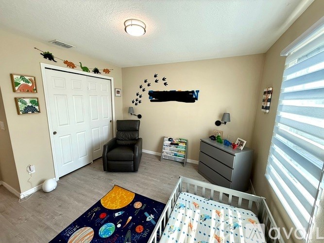 A baby room with a crib, chair, and decorations.