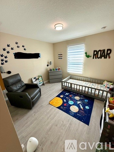 A living room with a black leather chair and a blue rug with planets on it.