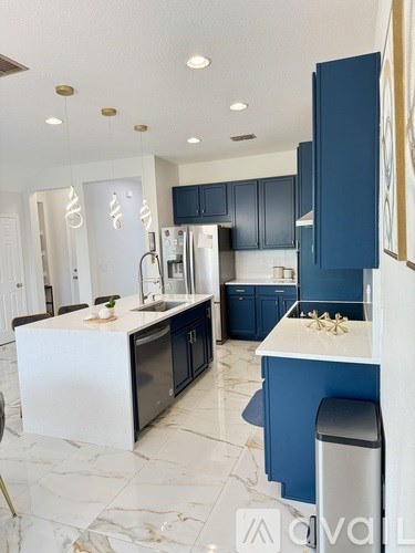 A modern kitchen with blue cabinets and a marble floor.