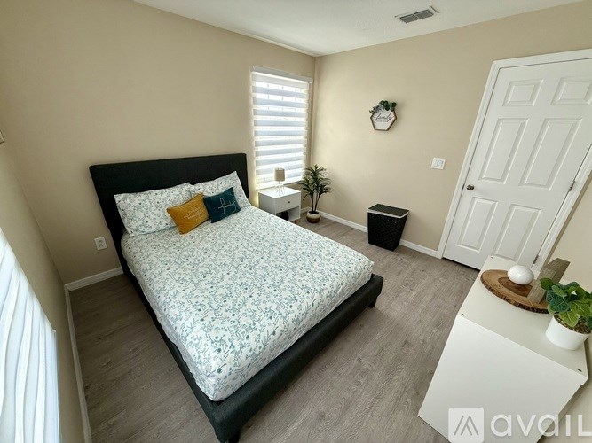 A bedroom with a large bed and a small plant on the nightstand.