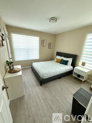 A bedroom with a bed, nightstand, and a plant on a small table.