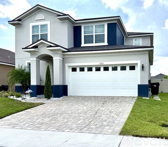 A two-story house with a white garage door and a blue trim.