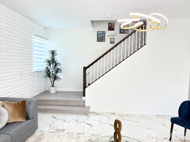 A living room with a grey couch, a staircase, and a plant.