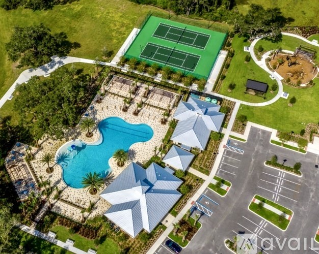 An aerial view of a resort with a tennis court, swimming pool, and parking lot.
