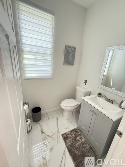A bathroom with a toilet, sink, and mirror.