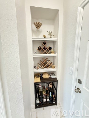 A small black cabinet with wine bottles on the bottom shelf.