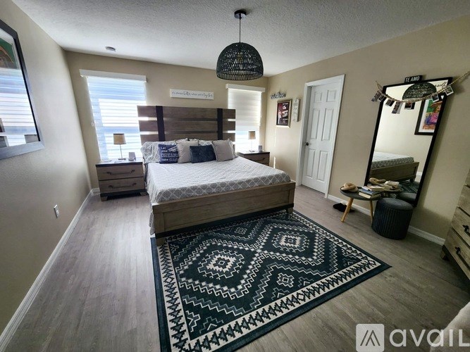 A bedroom with a bed, dresser, mirror, and rug.