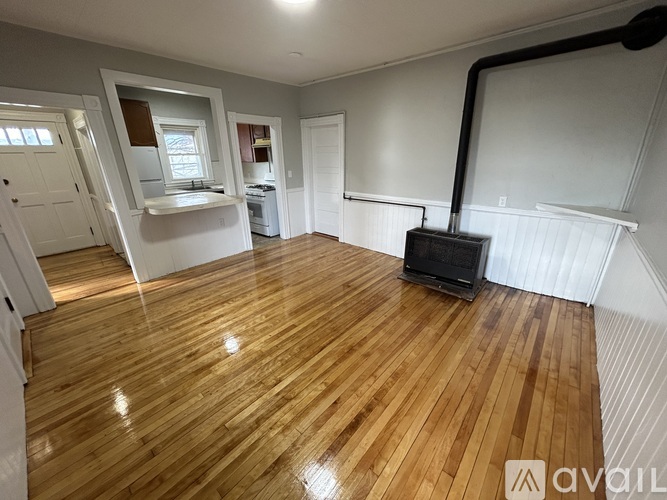 A room with wooden flooring and a black pipe running along the wall.