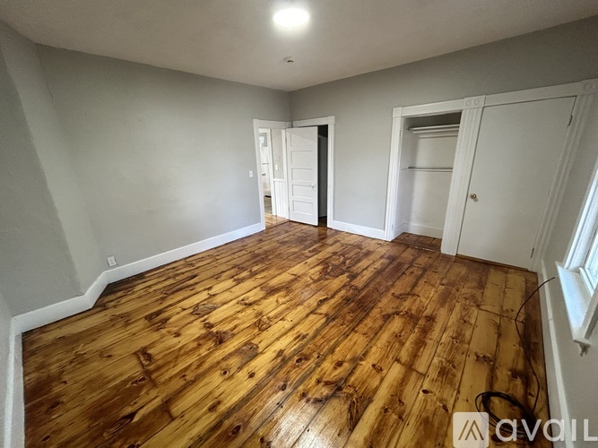 A room with wooden flooring and white walls.