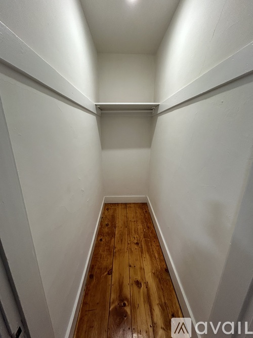 A long hallway with wood floors and white walls.