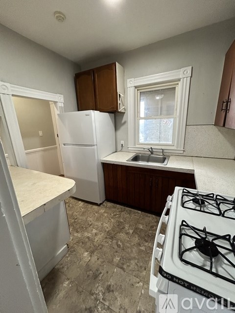 A kitchen with a white fridge, a white stove, and a window.