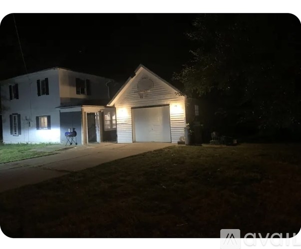A house with a garage is illuminated by its own lights at night.