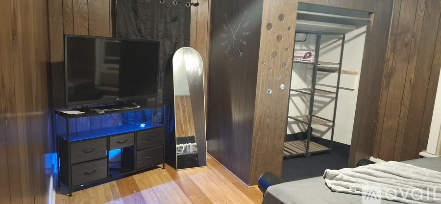 A room with a TV, drawers, and a bed.