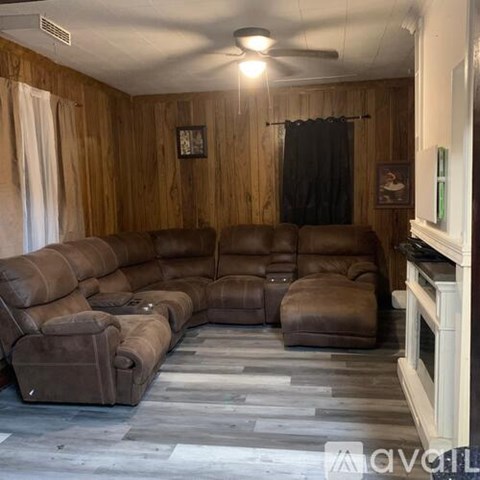 A living room with a brown leather couch and a fireplace.