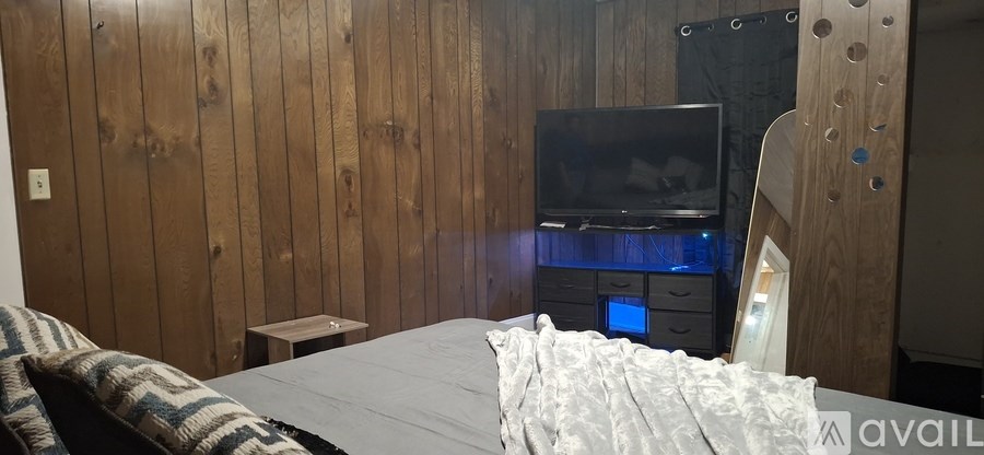 A bedroom with a bed, a TV and wooden walls.