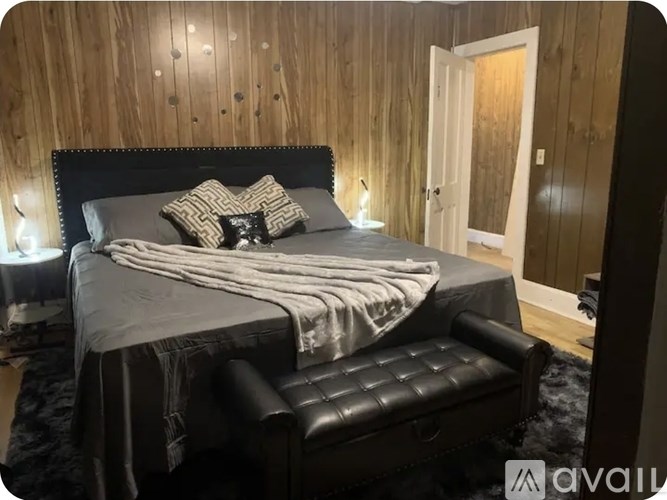 A bedroom with a bed, a chair, and a wooden wall.